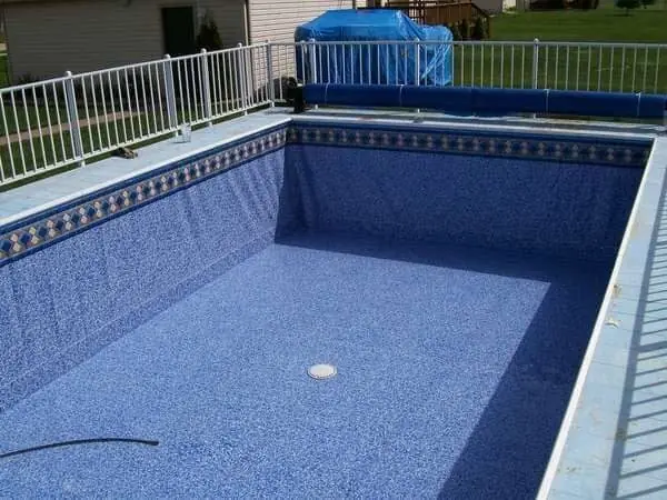Empty pool with a new patterned liner and a white fence