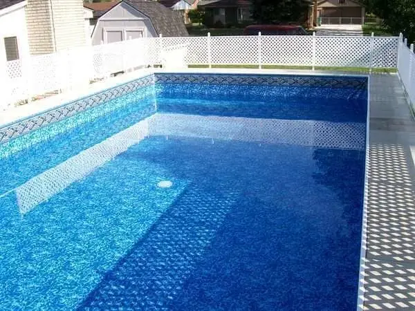 Pool interior with a blue liner and a lattice fence