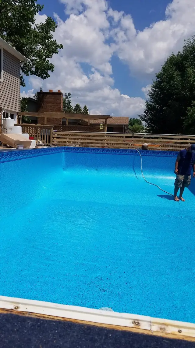A bright-blue new liner part way through filling, with a hose running in at the far end